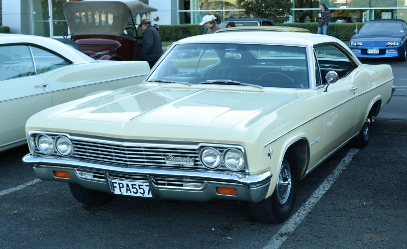 two older cars are parked in a parking lot