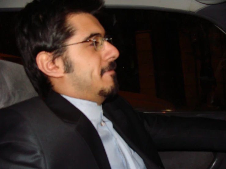 a man driving in a car and wearing a suit