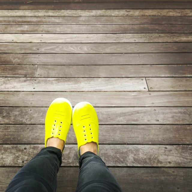 two feet wearing yellow shoes on a dock