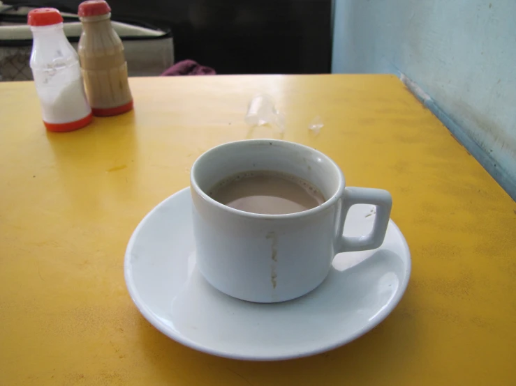 a cup and saucer on a yellow table