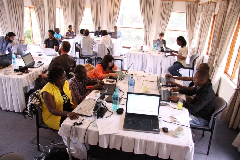 several people in a meeting room on laptop computers