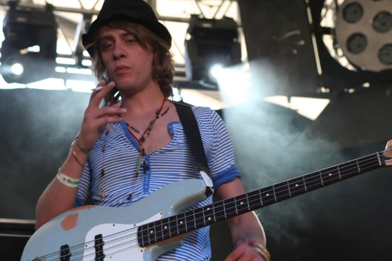 a man holding a bass guitar and smoking a cigarette