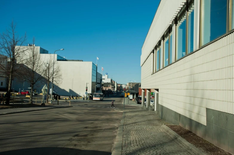 the road by a building is empty and has many cars parked on the street