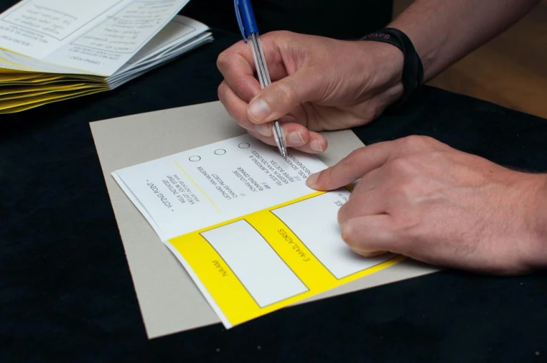 a person writing on a piece of paper with a pen