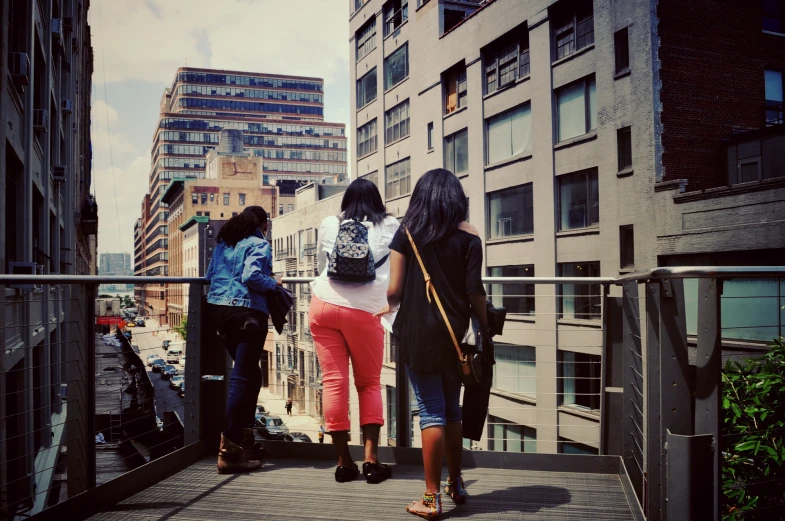 three women are walking across a bridge and some buildings