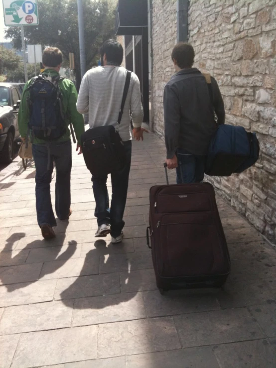 two guys walking and pulling their suitcases down the street