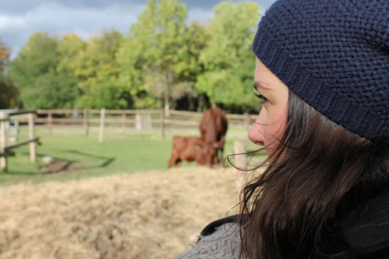 a person wearing a hat staring at a cow