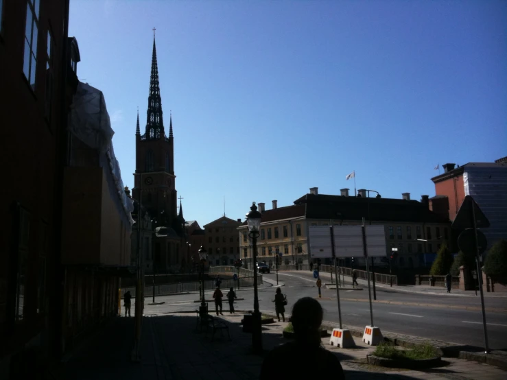 people walking on an empty street by a clock tower