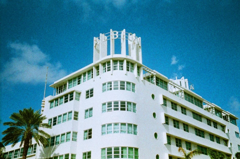 a large white building with many windows and palm trees