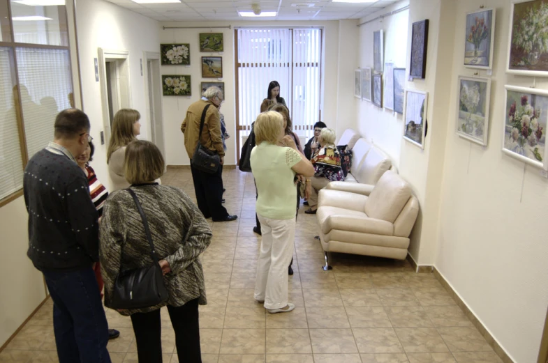 several people standing in a room looking at pictures on the wall