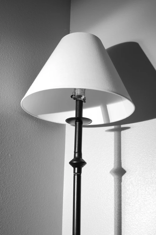 black and white pograph of lamp by wall