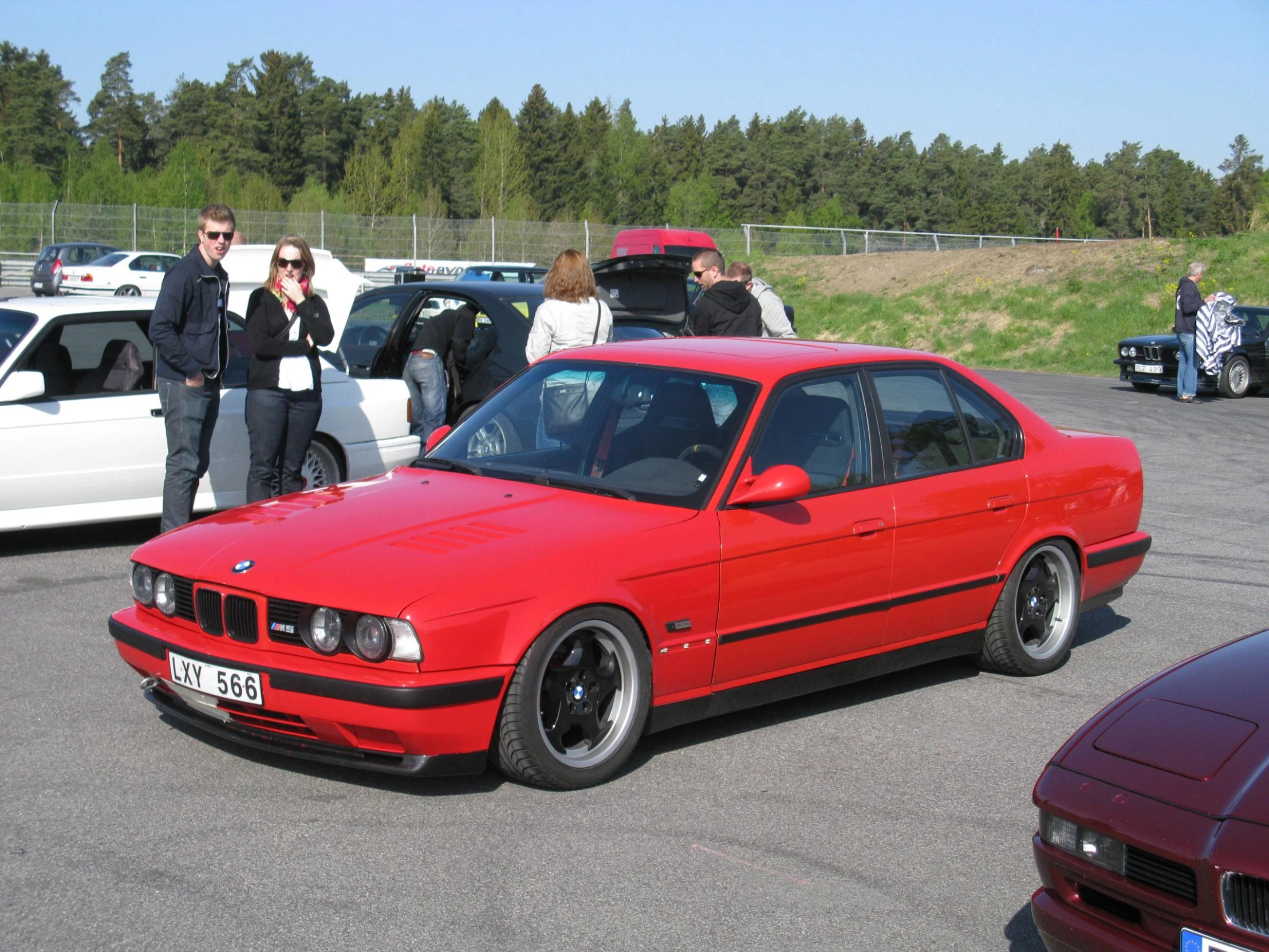 a red car in parking lot with several other vehicles