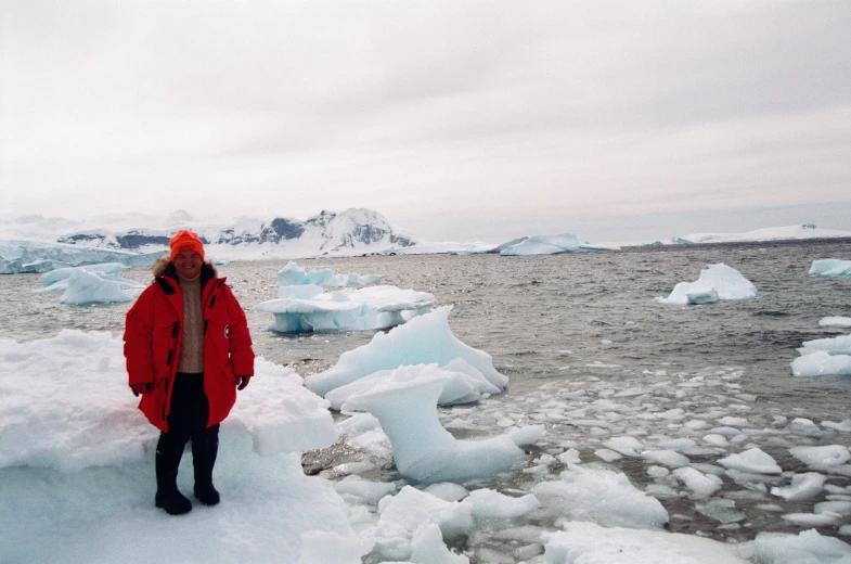 a woman wearing a red jacket standing on some ice