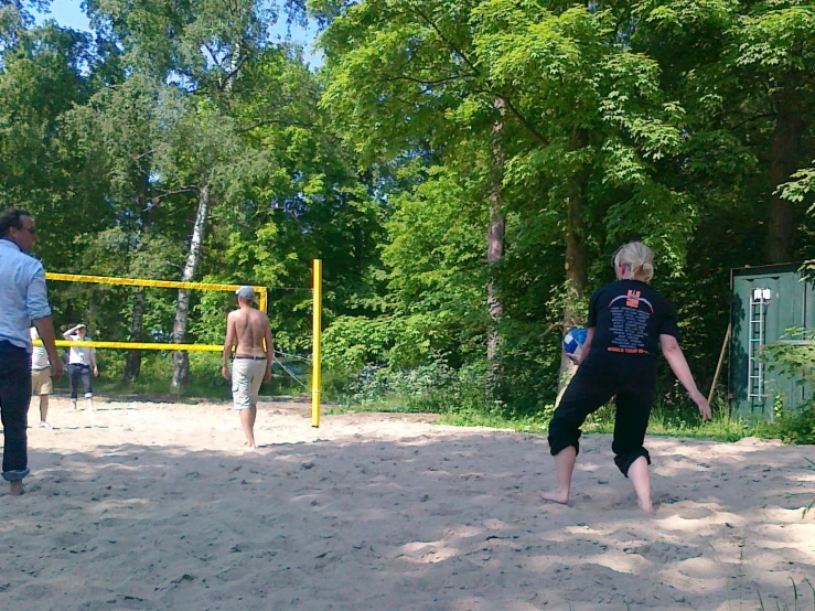 four men play with a frisbee in the sand