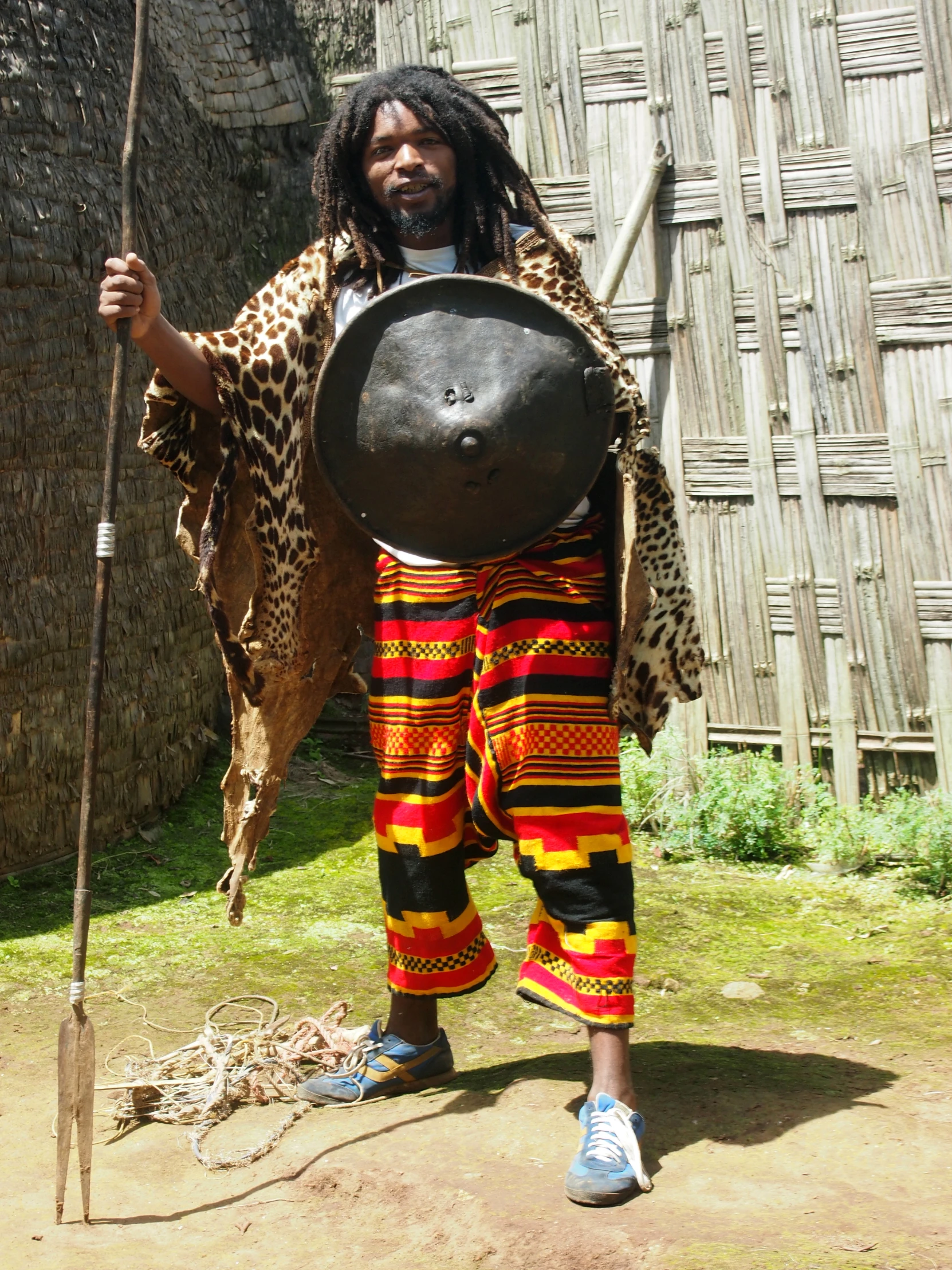 the african man with leopard print clothes has a long metal hat