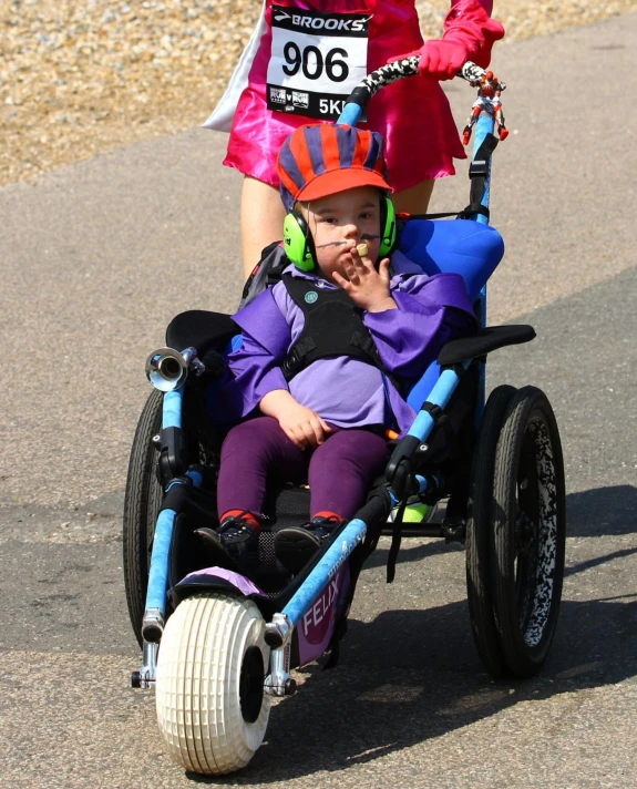 a young child in a motorized wheelchair riding along with a mother