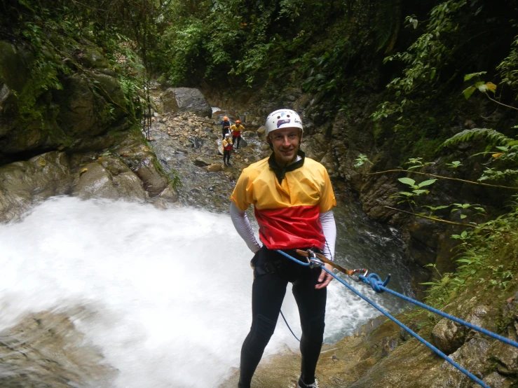 a man in yellow and black on rope above water