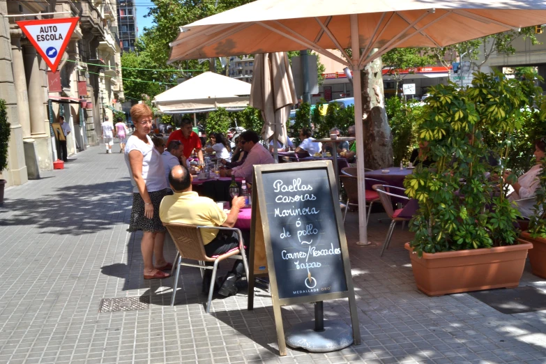 people are sitting at tables with umbrellas over them