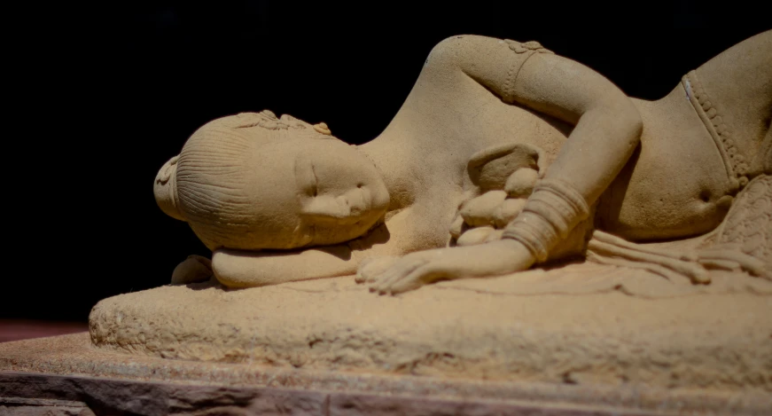 the sand is a sculpture that appears to be laying on its side