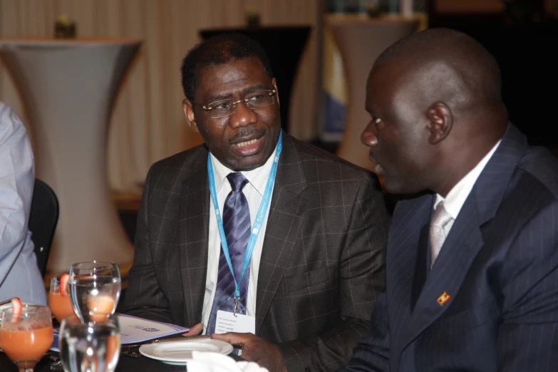 two men in suits and ties are seated at a table