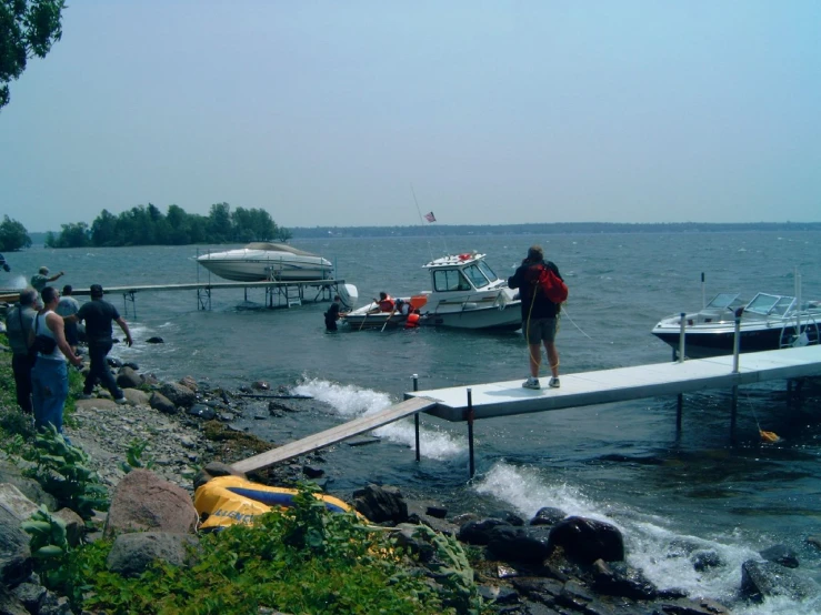 people standing on the edge of a dock next to boats