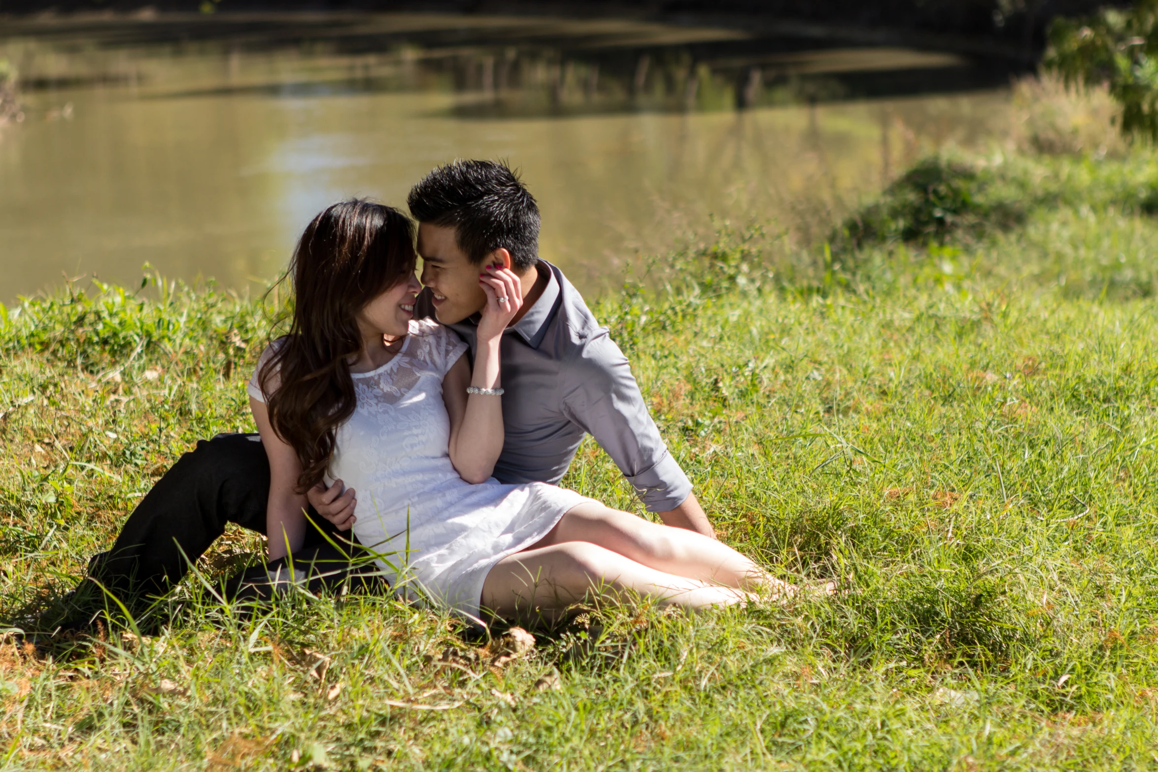 a man and woman sitting next to each other in front of water