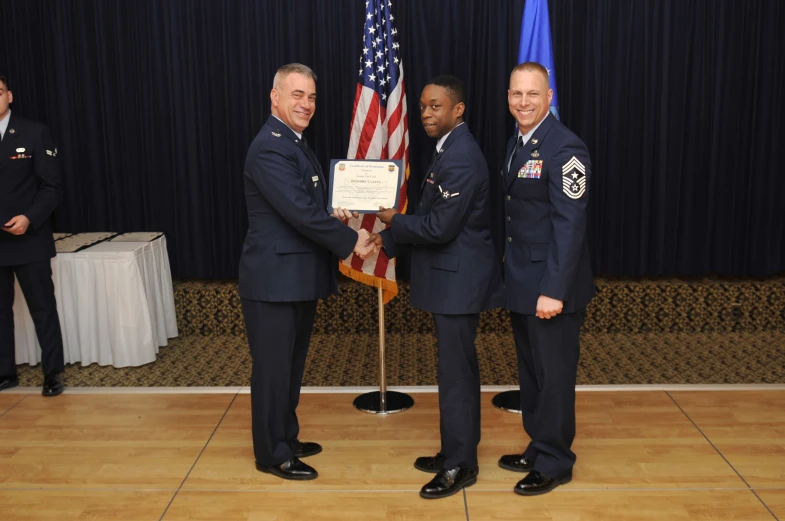 four men in uniform holding an award next to flags