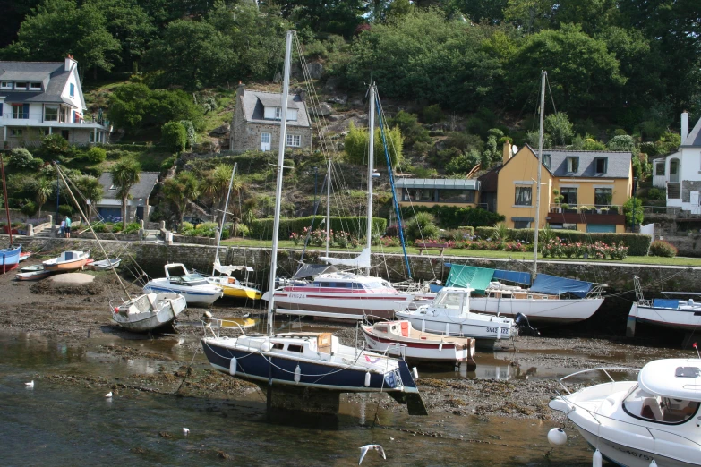small boats moored along a beach by a row of houses
