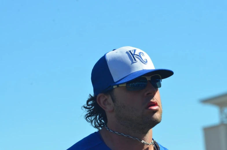 man in blue hat and sunglasses holding baseball bat