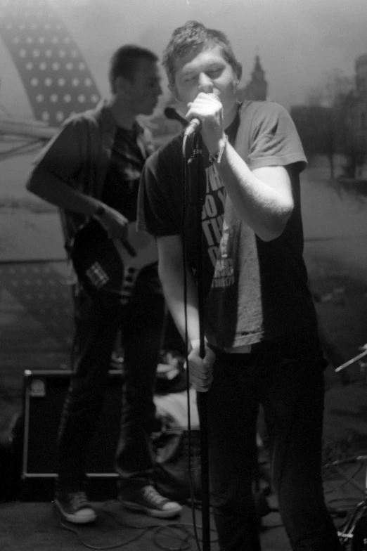 two men singing into microphones next to a flag