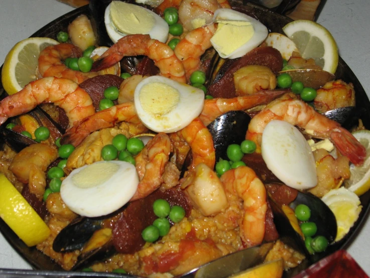 a pan filled with seafood and vegetables and topped with green peas