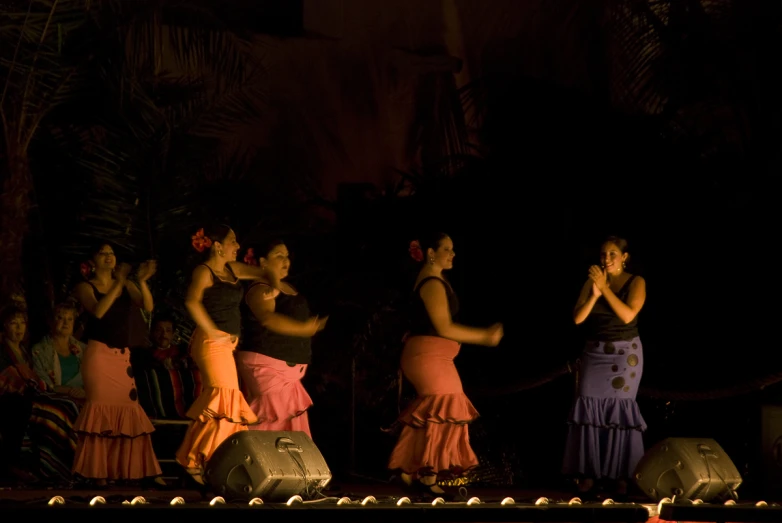 four women are dancing on stage at night