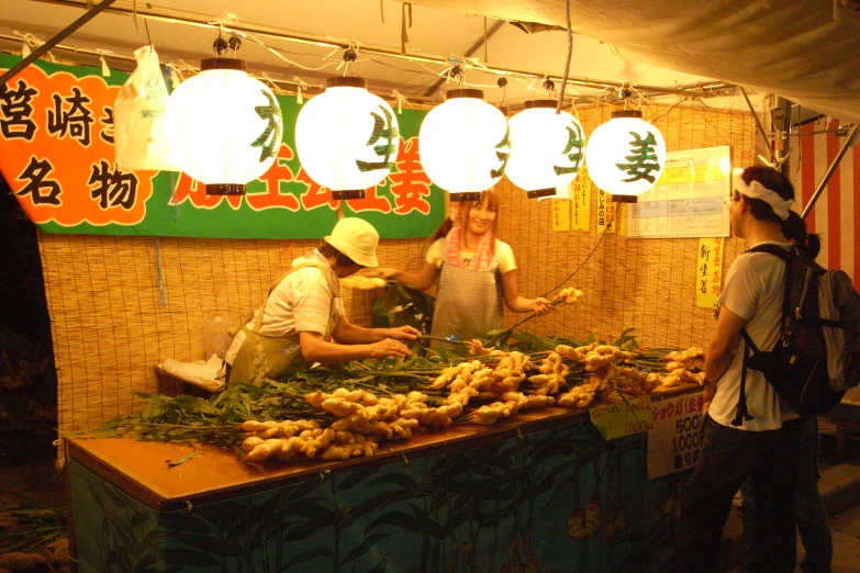 a woman and a boy at an outdoor market selling vegetables