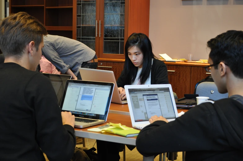 a group of people with laptops sitting around a table