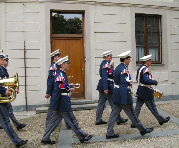 a group of men in uniform carrying musical instruments down a street