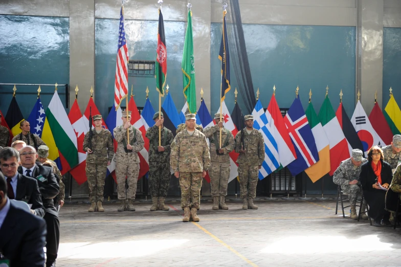 military men standing around with flags and other people