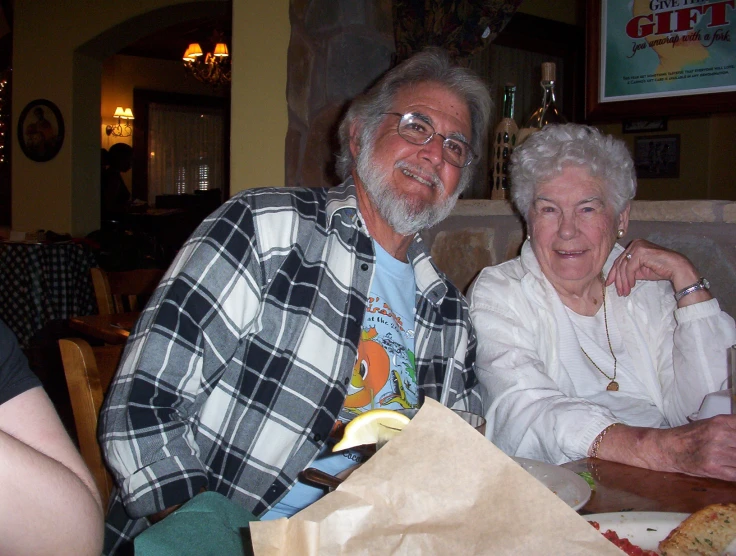 an older man and woman are seated at a table