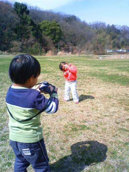 a little boy in blue and white shirt with camera and another person