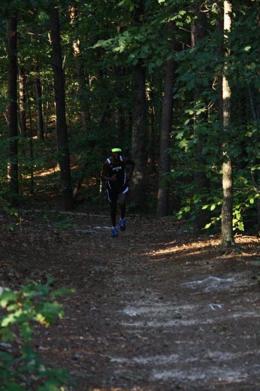 a man wearing a backpack is running on a forest trail