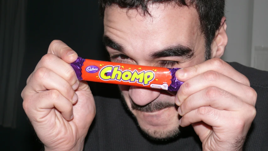 a man holding an orange candy bar with the word chummy on it