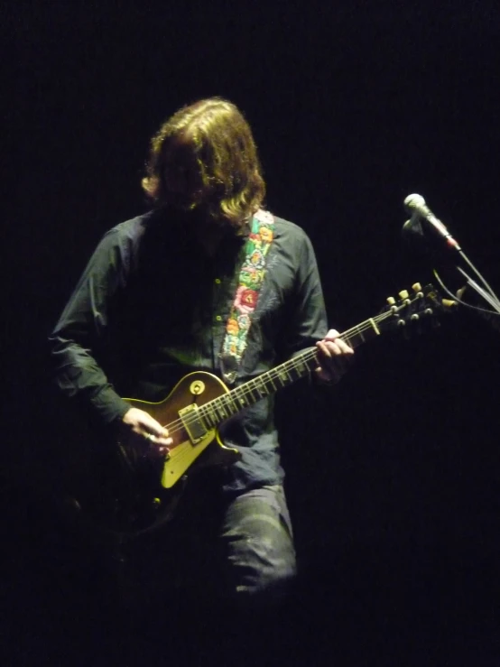 a man holding an electric guitar while he sings into the microphone