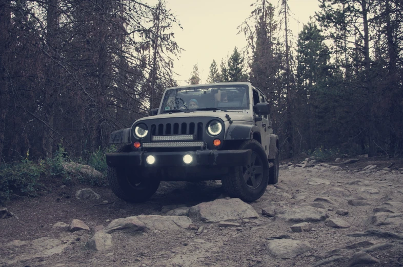 a black jeep is on rocky terrain with trees