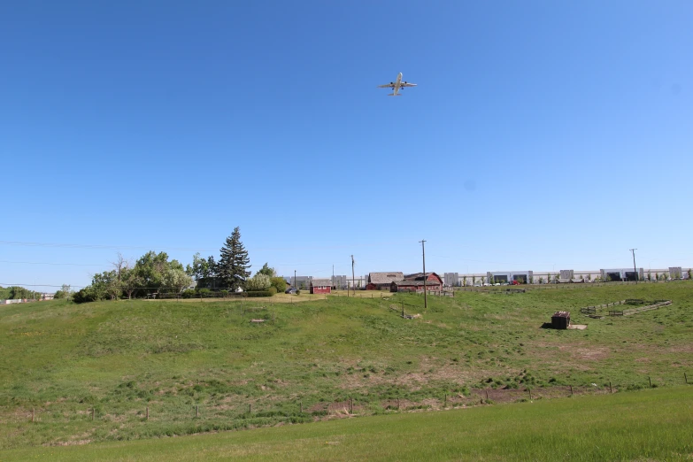 the plane is flying over the farm in the blue sky