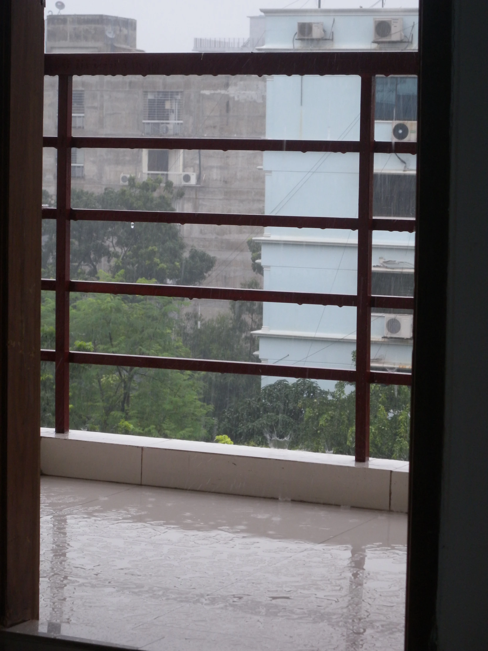 open window of urban city building with rain coming in