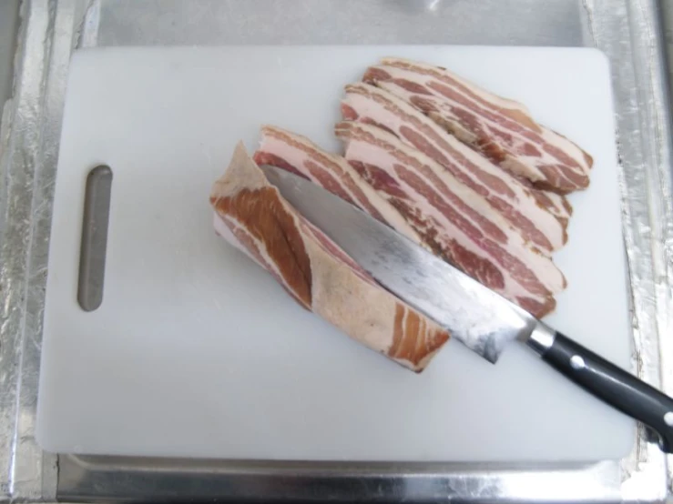 meat and knives on a  board next to another knife