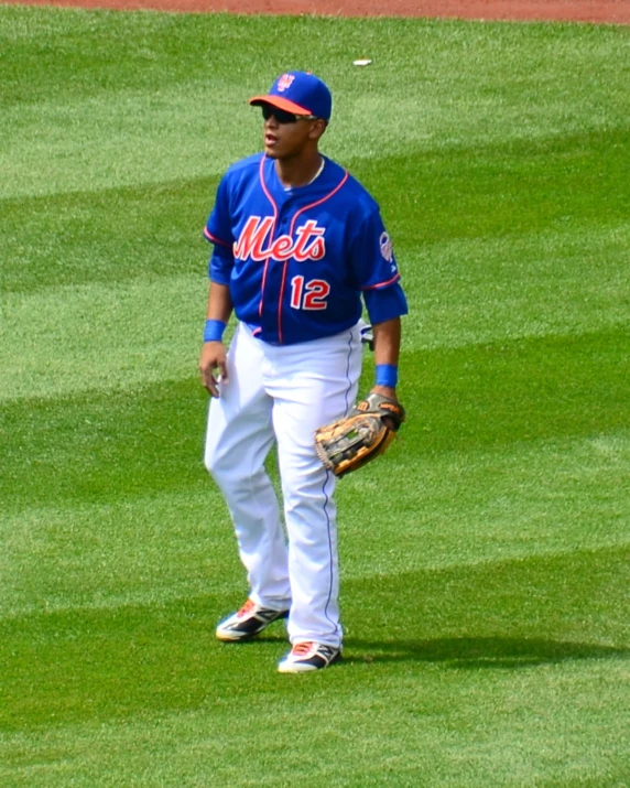 a baseball player standing on the grass with his glove