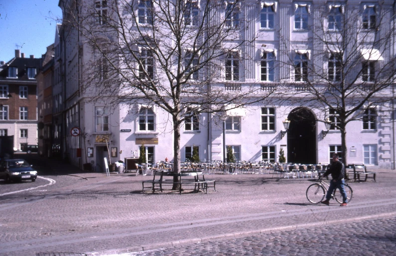 a bicyclist rides in the city as several benches and tables are set on the ground