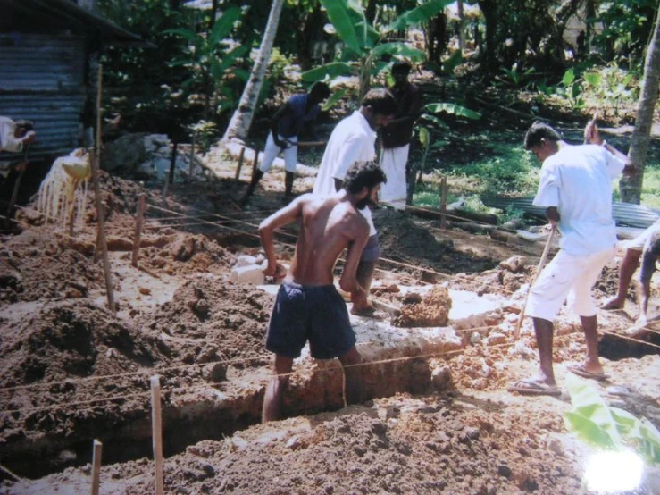 men are digging up some dirt and a fence