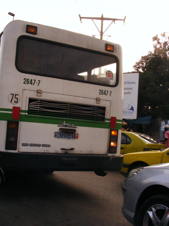 a white and green bus some cars and buildings