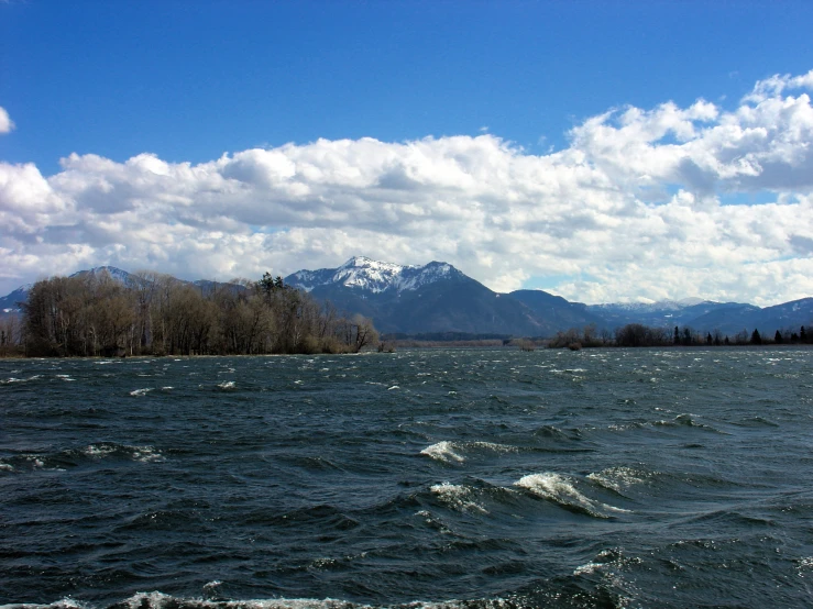 an island with a white capped mountains in the background